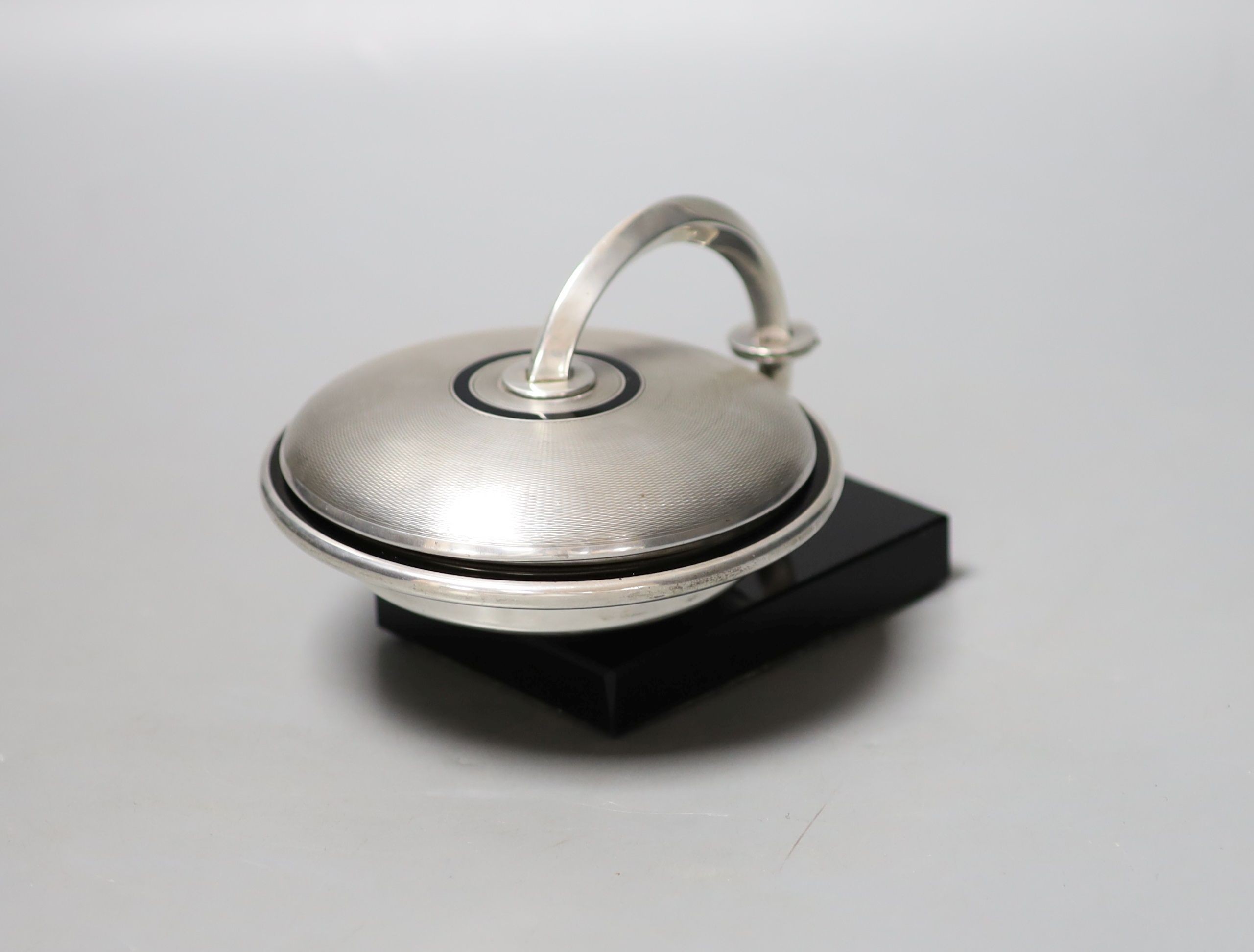 An unusual Art Deco engine turned silver and black enamel circular compact, with support arm, on black onyx? base (a.f.), Cohen & Charles, circa 1930, height 9.5cm.